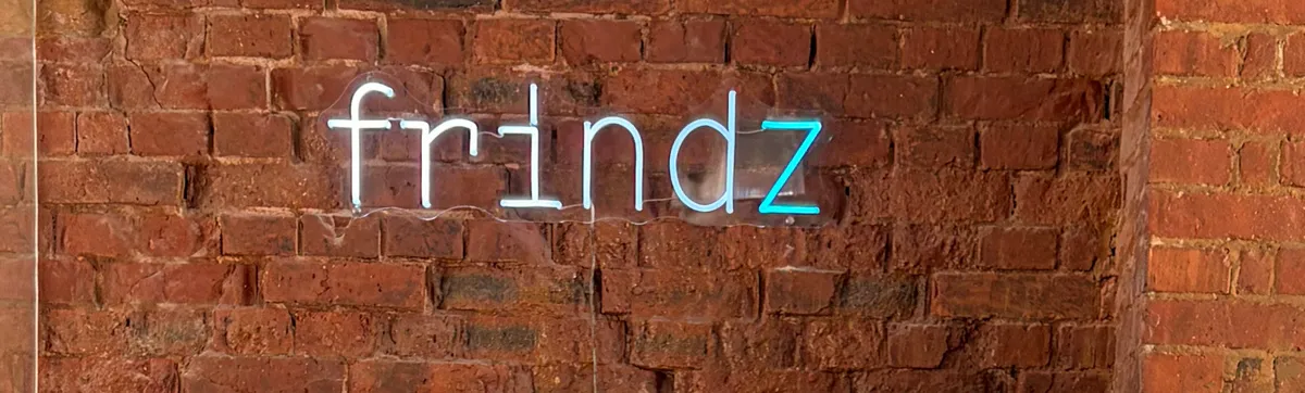 Die Leuchtschrift „frindz“ auf der Backsteinwand des Büros, das z leuchtet türkis.